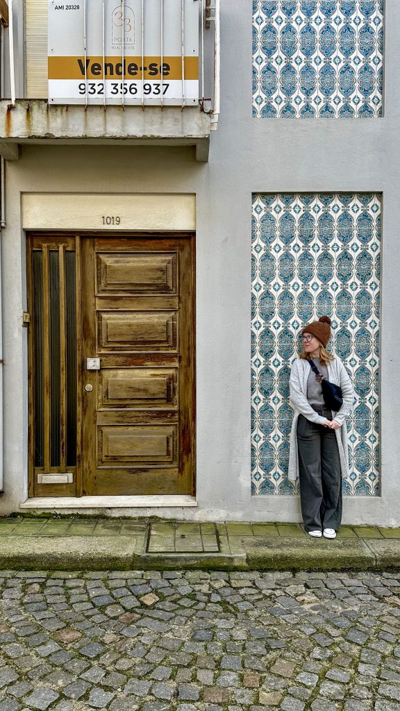 A woman standing against azulejos in Porto, Portugal