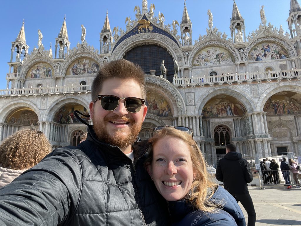 A couple in front of the Saint Mark's Basilica in Venice wearing winter coats