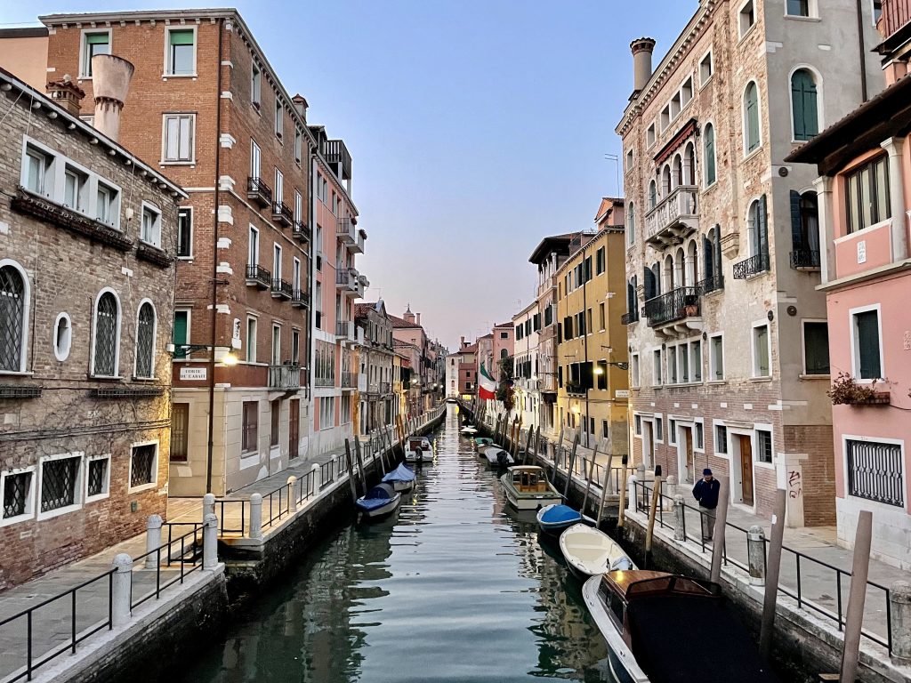 Colorful buildings lining a canal with small boats in Venice, Italy
