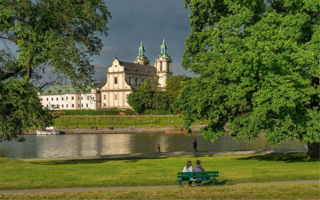 People sitting on a bench looking at the Vistula River in the Podgorze neighborhood of Krakow